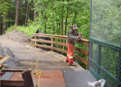 A worker finishing up a guard rail along an access point that takes trail users under University Way.